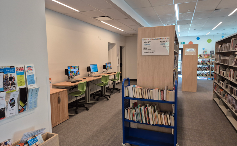 Interior of Fort Langley Library featuring a cart filled with books and several computers for public use.