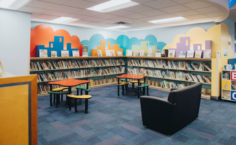  Interior of Clearbook Library's children's area featuring colorful walls and vibrant chairs for a lively reading environment.