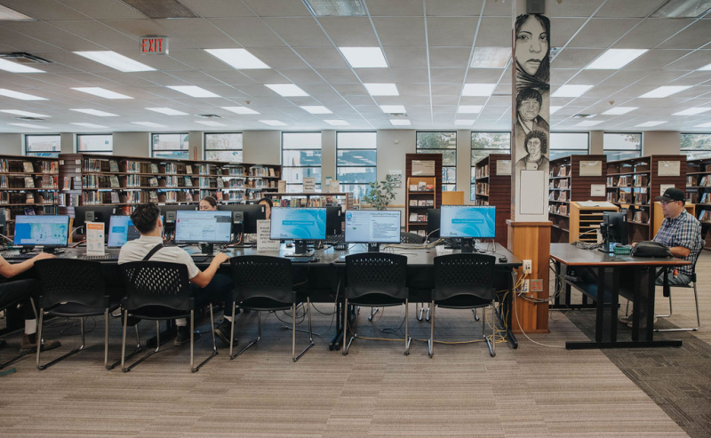 Interior of Mission Library with people working at desks and using computers, creating a focused study environment.