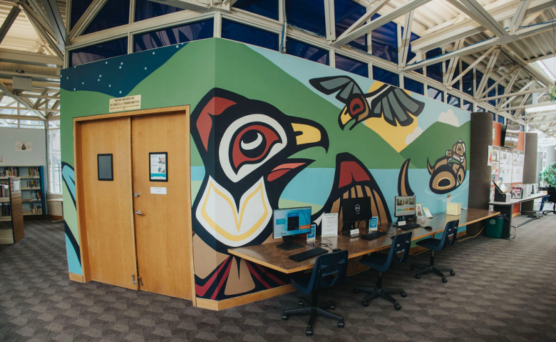  Interior of Chilliwack Library featuring an indigenous mural of birds and a otter painted on the wall.