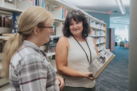 A library staff member helps a customer choose a book at Maple Ridge Public Library.