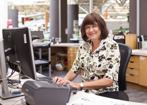 A female FVRL employee works at a service desk in Chilliwack Library.
