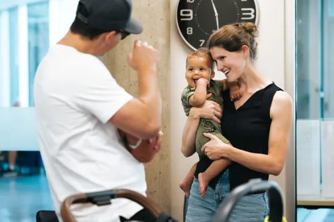 Mingling after Storytime at Terry Fox Library: a man waves to a a baby being held in his mother's arms.