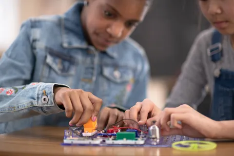 Two tweens work together to learn coding using a Snap Circuit board.