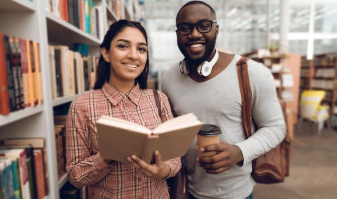A young woman and a young man are looking for books in a library.
