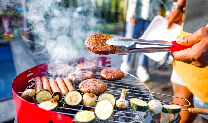 Burgers, hot dogs and vegetables sizzle on a backyard grill.