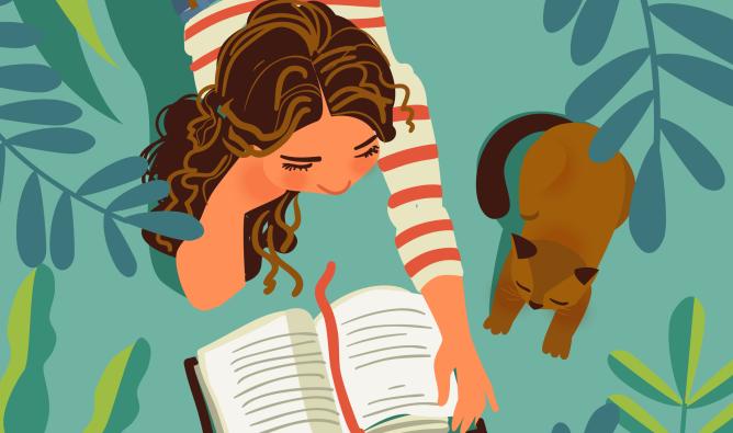 A teenage girl reads a book on the grass. A brown cat stretches next to her. There are leaves all around.
