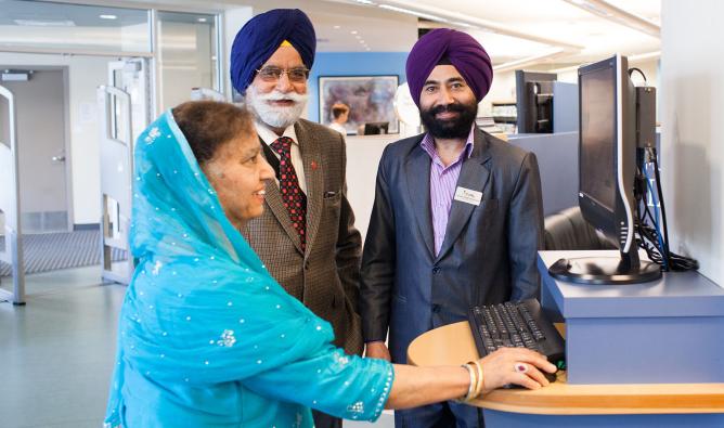 An FVRL staff member helps a Punjabi couple at Muriel Arnason Library.
