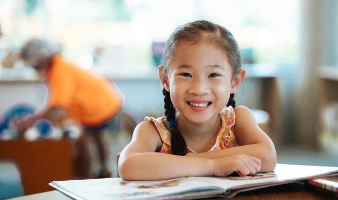 A young girl poses with an open storybook at Terry Fox Library