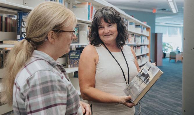 A staff member helps a customer choose a book at Maple Ridge Public Library.